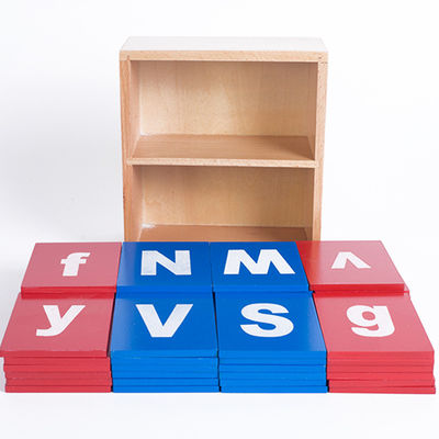 Montessoriの木のアルファベットのたどる板を学んでいる赤ん坊